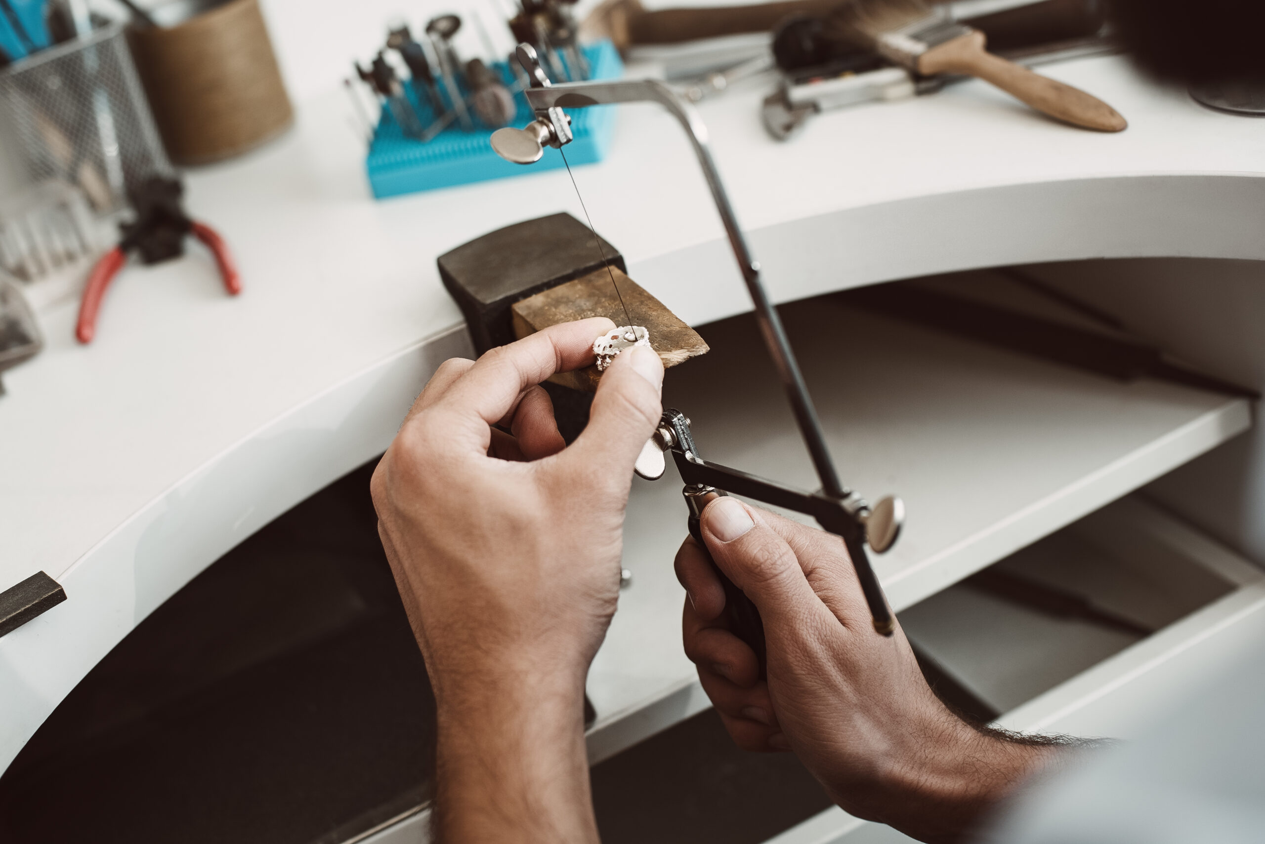 Confident motion. Close-up photo of jeweler's hands making a silver ring with professional adjustable jeweler's saw frame Anello oro Gioielleria Farina Torino